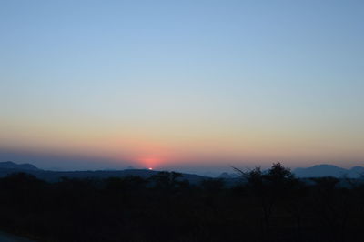 Scenic view of silhouette mountains against orange sky