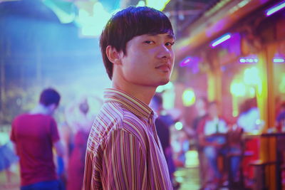 Portrait of man standing in illuminated market at night