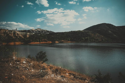 Scenic view of lake by mountains against sky