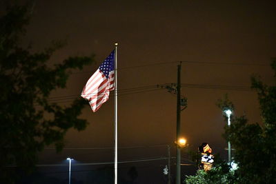 Flag on street against sky in city at night