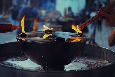 Close-up of hand igniting incense at temple