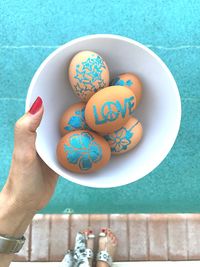 Close-up of hand holding painted easter eggs in bowl