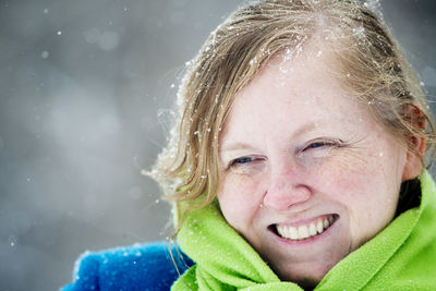 Close-up of mature woman smiling during snowfall