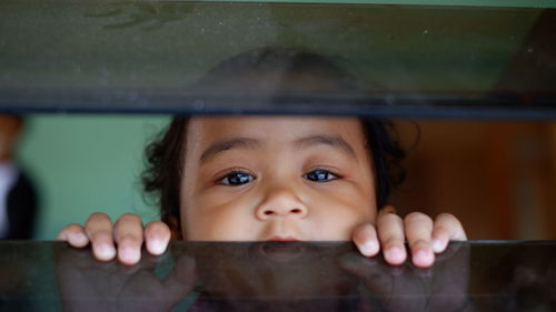 Portrait of cute boy looking through window