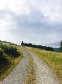 Road amidst field against sky