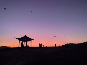 Silhouette of traditional windmill against sky during sunset