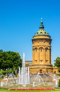 Fountain in front of built structure against clear blue sky