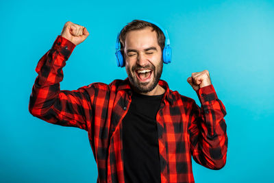 Portrait of young man standing against blue background