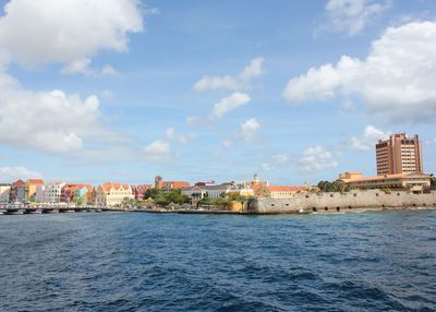 Sea by buildings against sky in city