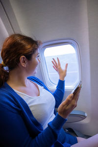 Woman looking at camera while sitting in airplane