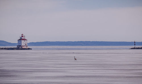 Lighthouse by sea against sky