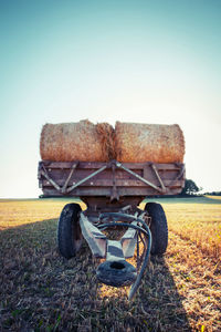 Hay bales on vehicle trailer against clear sky at farm