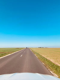 Road leading towards blue sky