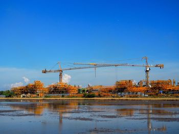 Cranes at construction site against clear blue sky