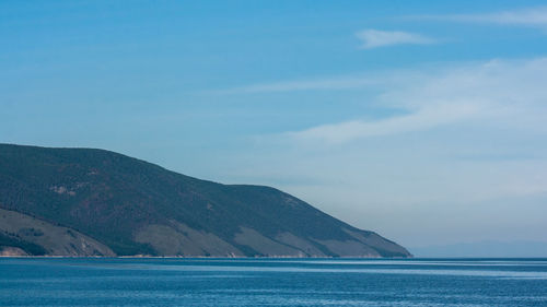 Scenic view of sea by mountains against sky