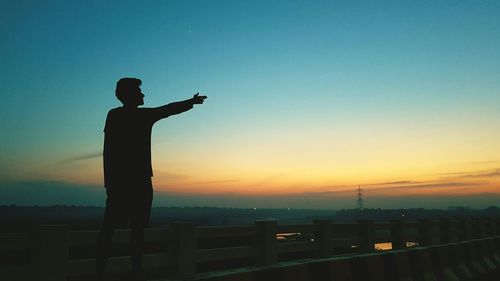 Silhouette man standing against clear sky during sunset