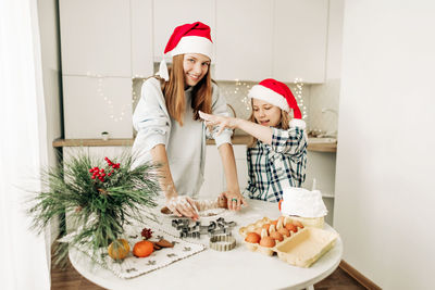 A cute girl helps her older sister prepare a christmas dessert, the girls bake cookies 