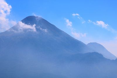 Low angle view of volcanic mountain against blue sky