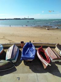 Lounge chairs on beach against blue sky