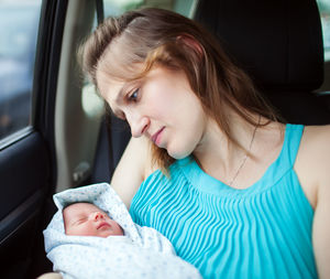 Mother looking at cute son sleeping while sitting in car