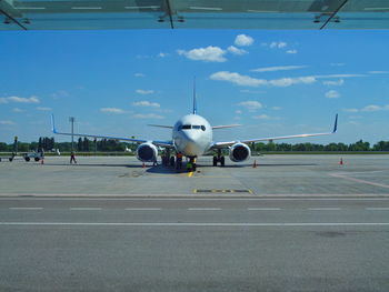 Airplane on airport runway against sky