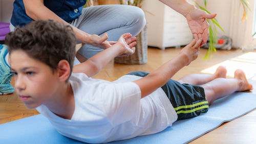 Lower back stretch. boy exercising with physical therapist.