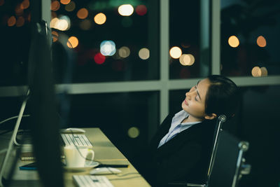 Woman sitting on illuminated smart phone at night