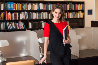 Professional woman educator or manager posing at public library of high school or college