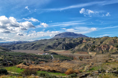 Scenic view of landscape and mountains against blue sky