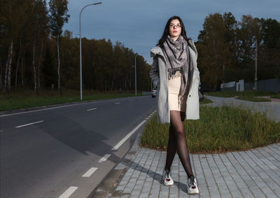 Portrait of woman standing on road against trees