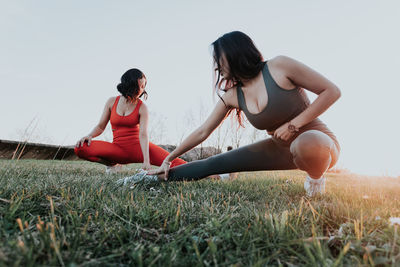 Side view of woman sitting on grassy field