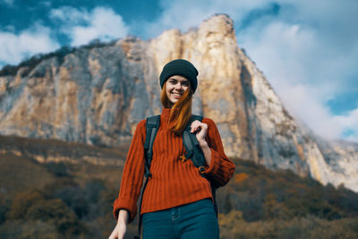 Young woman wearing hat standing against mountain during winter