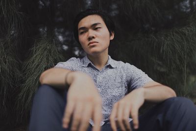 Low angle view of thoughtful man sitting by tree