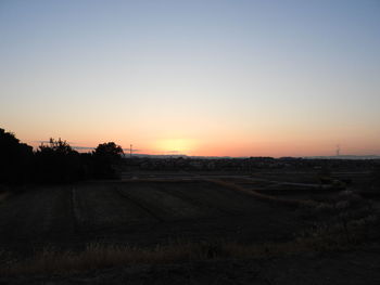 Scenic view of agricultural field against clear sky during sunset