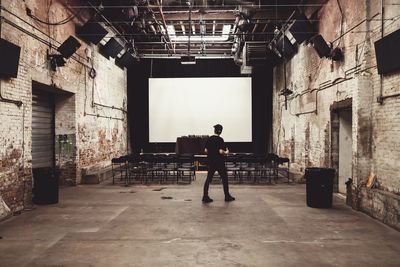 Full length of man walking against projection screen in studio