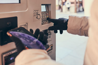 Woman buying parking ticket at park machine using smartphone and contactless method of payment