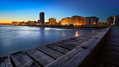 Jesolo seaside seen during the blue hour after sunset andblue sky- city lights from the wooden jetty