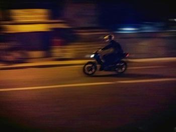 Blurred motion of man riding motorcycle on road