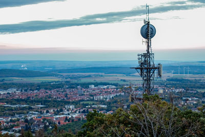 Communications tower in city against sky