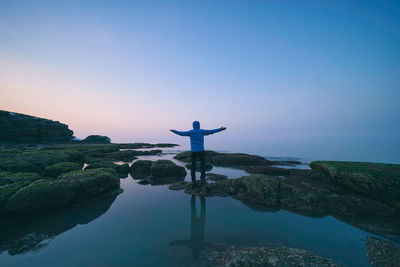 Rear view of man looking at sea against sky during sunset