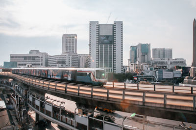 View of train in city buildings against sky