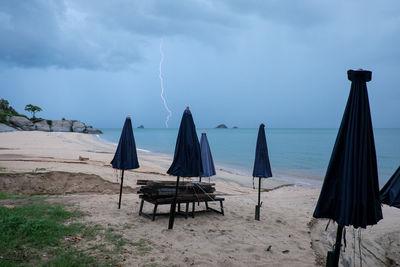 Deck chairs on beach against sky