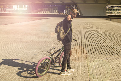 Portrait of man with bicycle standing in city 