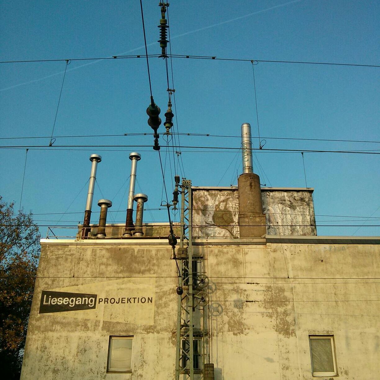 architecture, low angle view, building exterior, built structure, communication, power line, blue, cable, clear sky, sky, text, electricity, street light, guidance, electricity pylon, day, outdoors, no people, city, tower