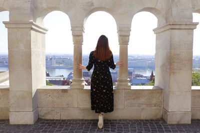 Rear view of woman standing by arch against sky