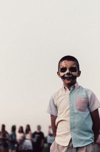 Portrait of boy with evil face paint against sky