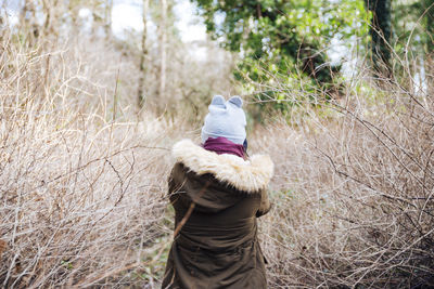 Rear view of woman standing in forest during winter