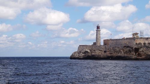 Lighthouse by sea against sky