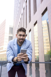 Smiling businessman using mobile phone outdoors