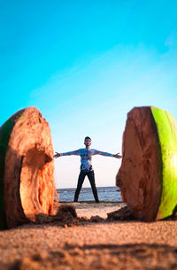 Man standing on rock against blue sky